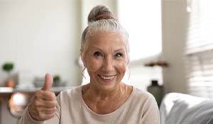 Woman with dental implants in Indian Land giving thumbs up