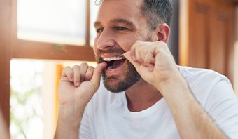 Man smiling while flossing his teeth
