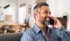 Man smiling while talking on phone at home