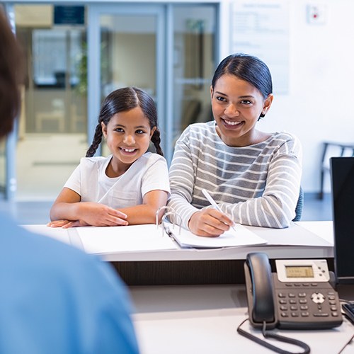 Mother and daughter checking in at reception desk