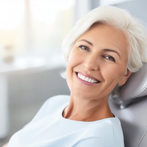 a denture candidate smiling while sitting in the dentist’s chair
