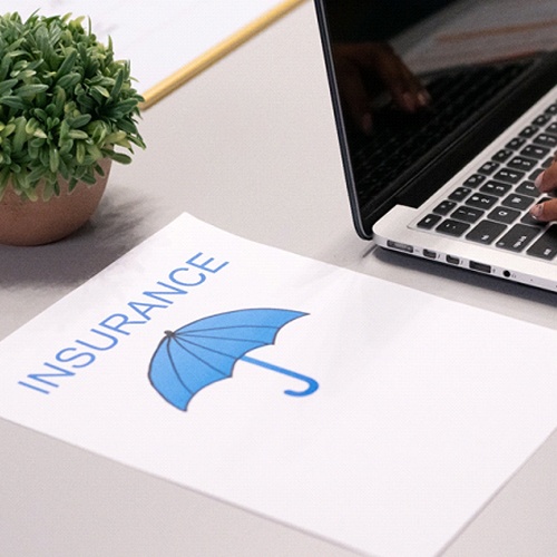 Insurance paper next to woman using laptop