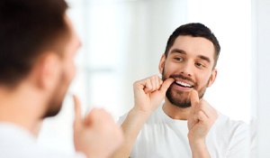 man flossing in front of a mirror