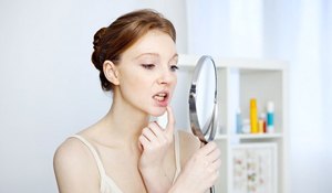 woman looking at her tooth in a mirror