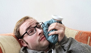 man holding an ice pack to his cheek