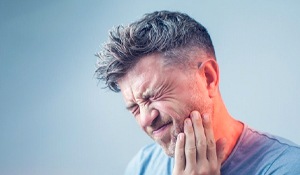 man holding the side of his mouth in pain
