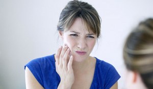 woman with jaw pain looking in the mirror