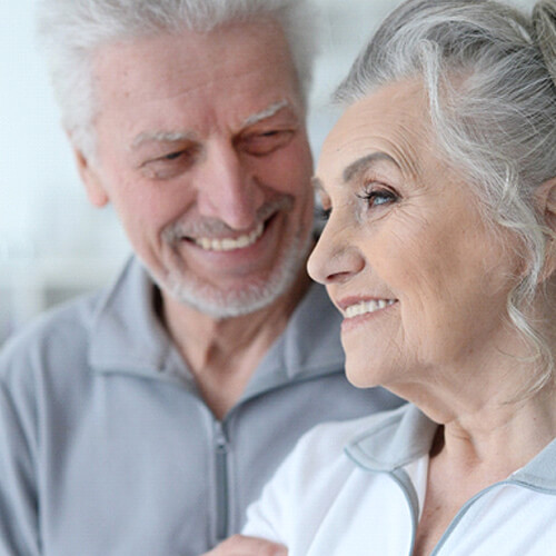 An older couple standing next to each other and smiling over the benefits of dental implants in Indian Land