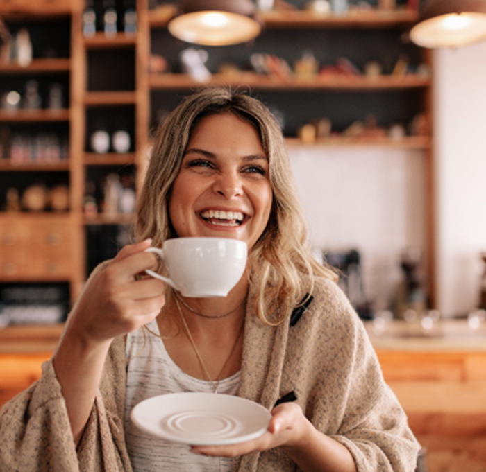 Woman smiling while enjoying coffee at restaurant