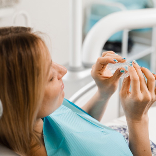 Patient holding clear aligner in treatment chair
