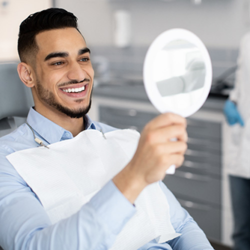 Man smiling at reflection in mirror in treatment chair