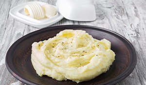 Mashed potatoes on a hot plate next to butter
