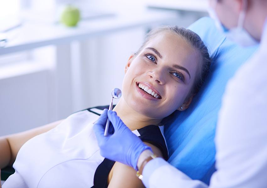 Woman in dental chair smiling at dentist