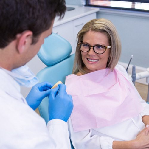 woman sitting in dental chair talking to dentist  