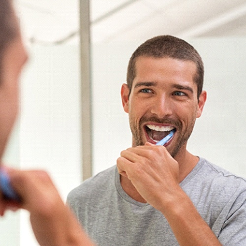 Closeup of man smiling while brushing his teeth