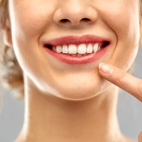 close up woman pointing to her smile