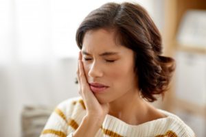 person holding their mouth because they have a toothache in Indian Land