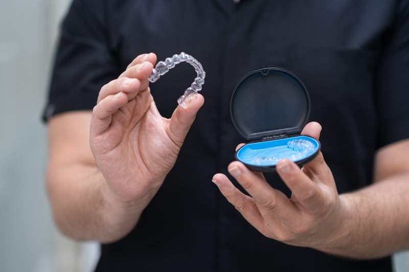 An orthodontist taking out clear aligners from a case