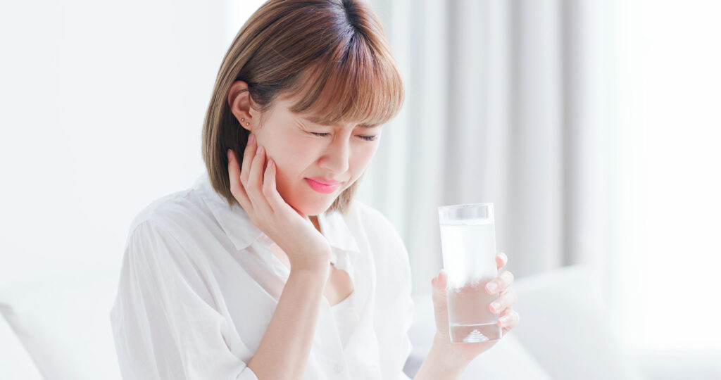 Patient holding their cheek due to tooth sensitivity