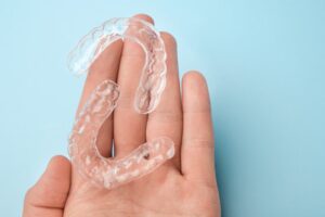 Hand holding pair of clear aligners.